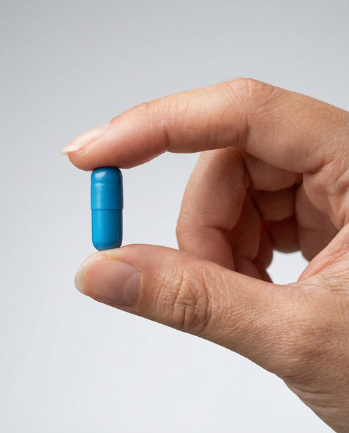 Person holding Megamind nootropic capsule between fingers